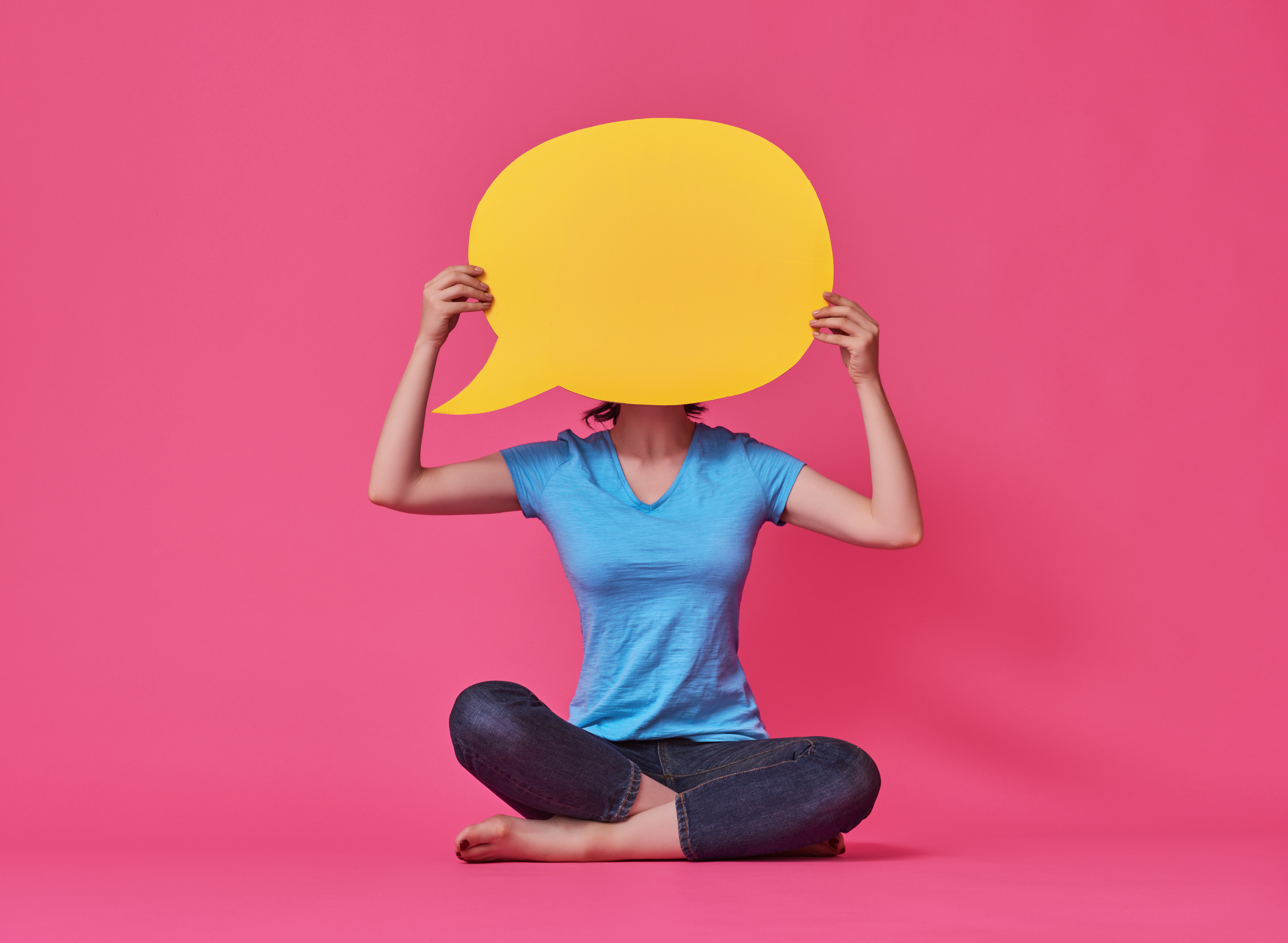 Woman holding a yellow speechbubble behind pink background