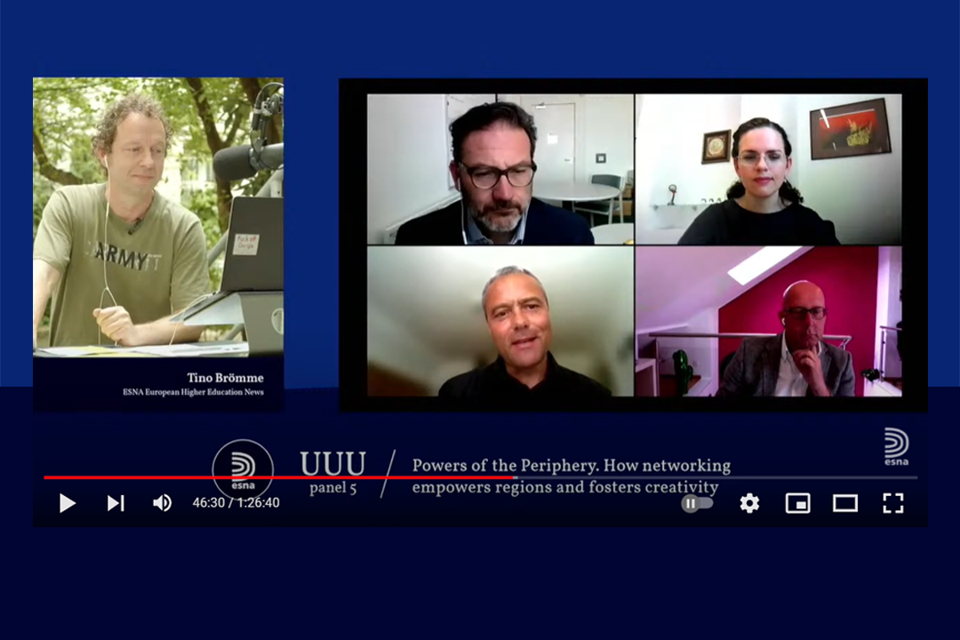 People walking through a bright indoor hallway with glass walls and shops.