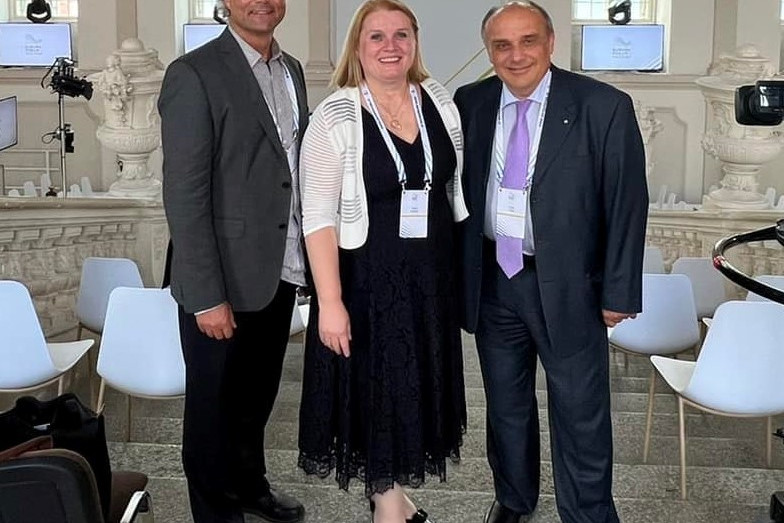 People walking through a bright indoor hallway with glass walls and shops.