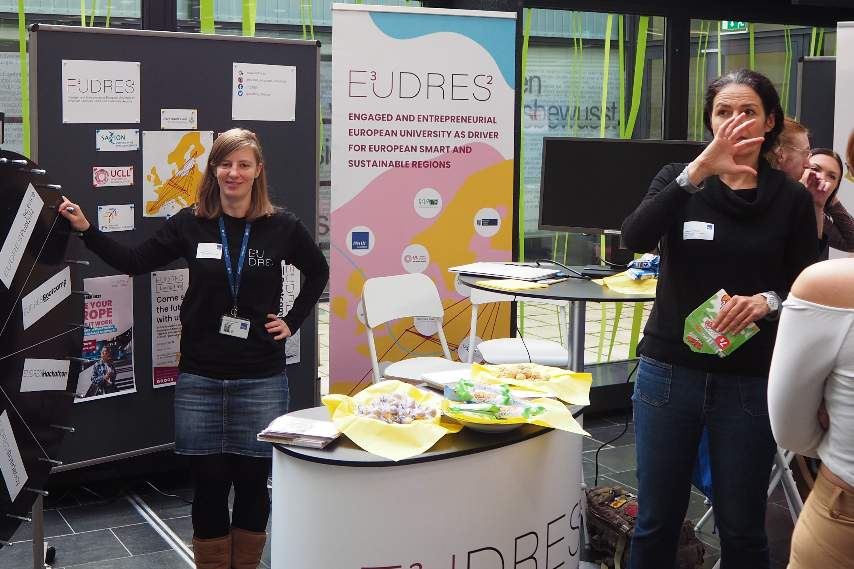 People gathered around standing tables at a networking event with food and drinks.