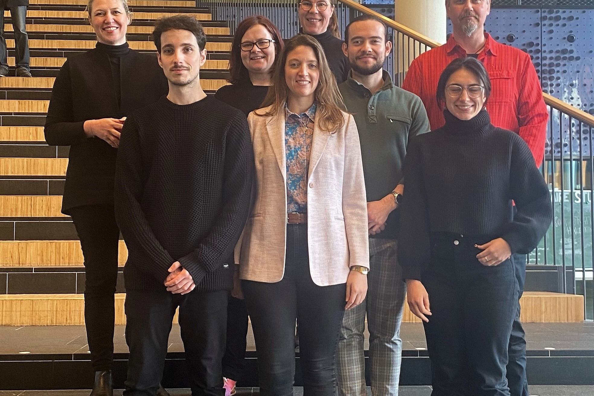 People walking through a bright indoor hallway with glass walls and shops.