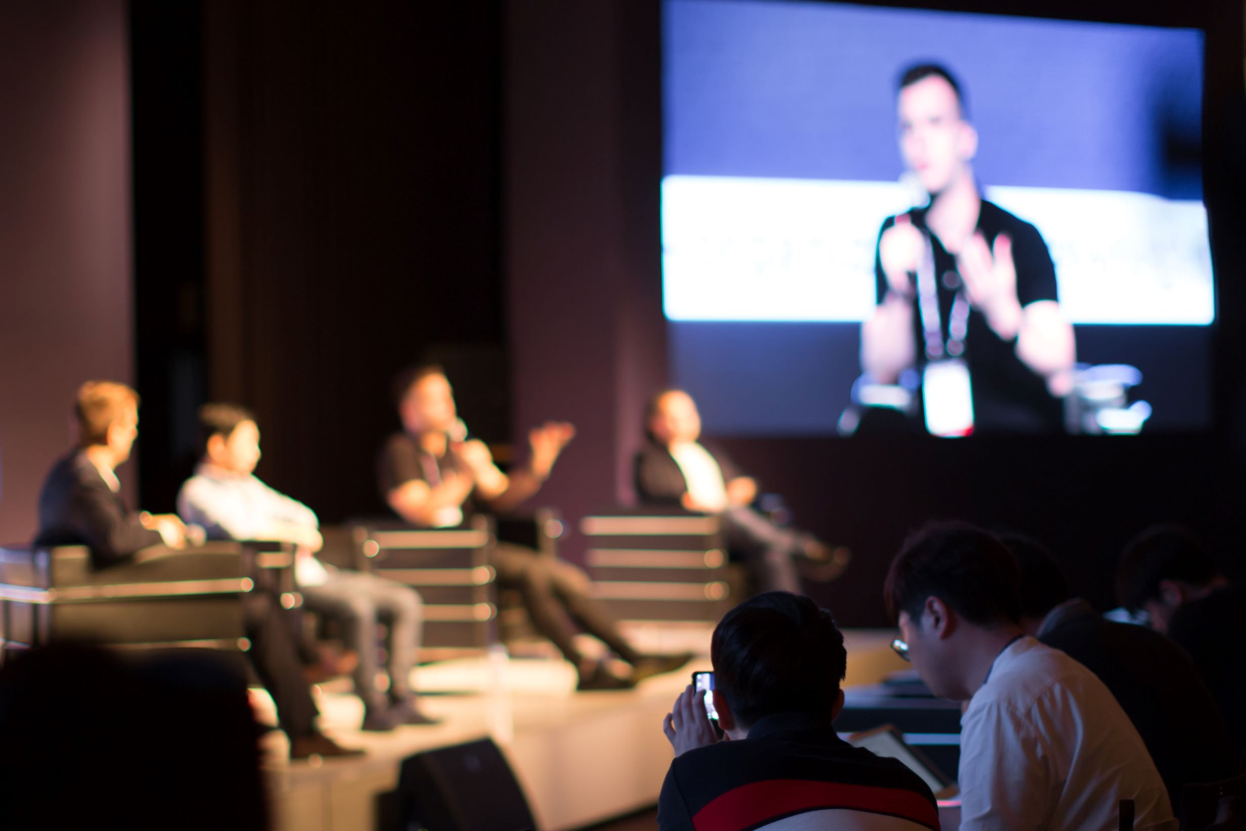 Audience members watching a panel discussion on stage at a conference.