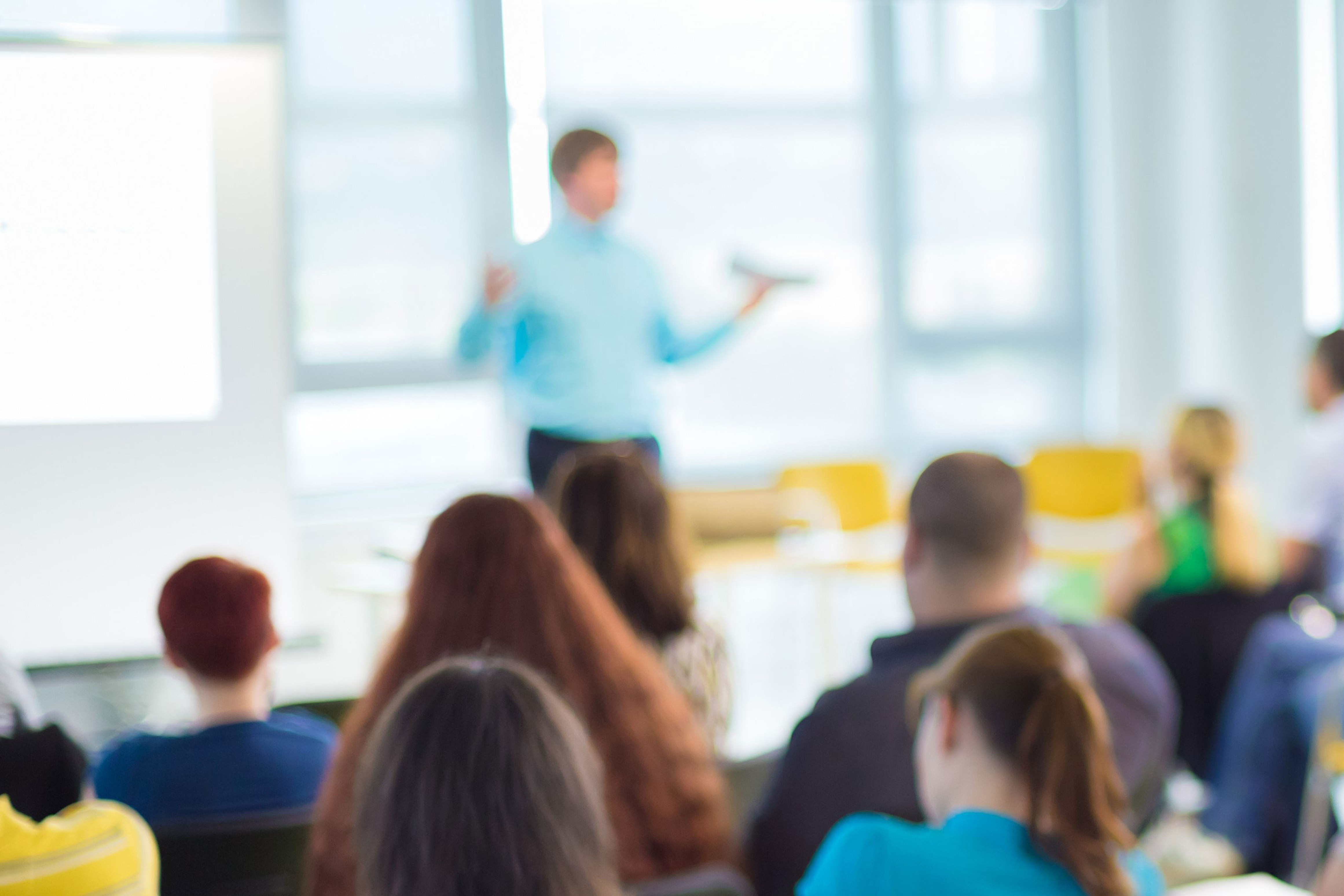 blurred photo of audience watching a presenter.